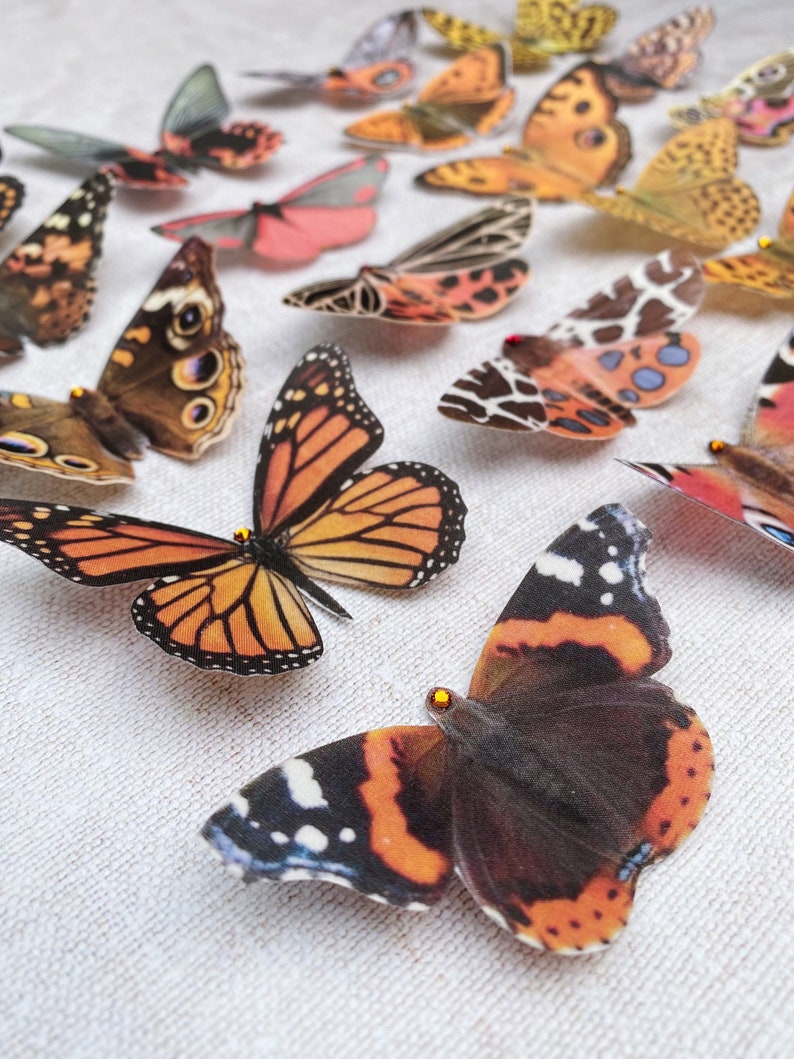 An image of brown silk butterfly hair clips, in the foreground is a super realistic Red Admiral butterfly and a gorgeous monarch.