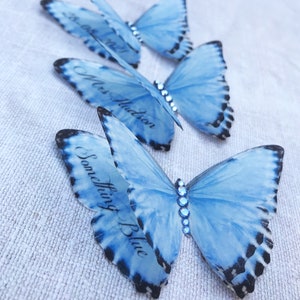 Three silk butterflies each with custom words printed on the lower wings. One has a date, another a name and the last the words something blue.