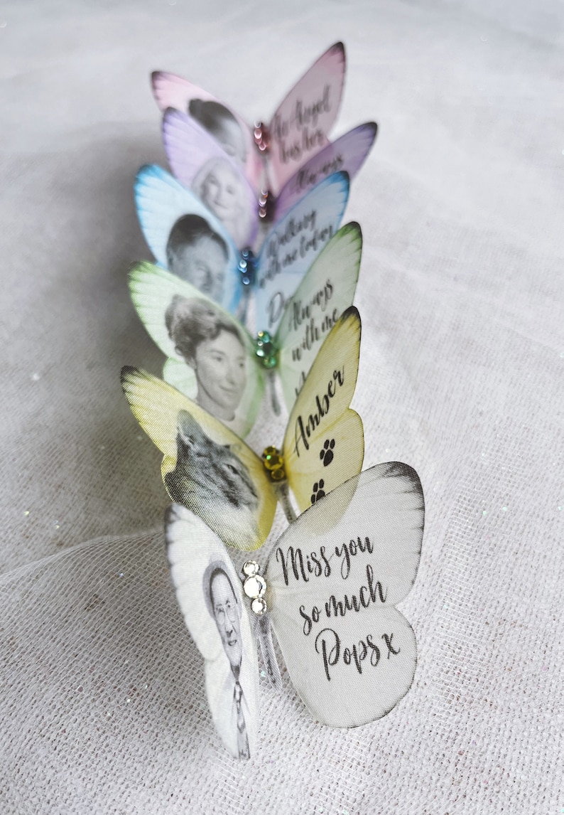 Silk butterfly wedding keepsake pins all lined up on a linen cloth. The delicate  pastel colours like a subtle rainbow. each one customised with an image and words of your choice