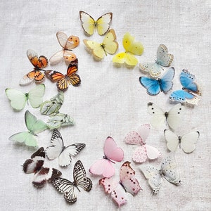 A oatmeal coloured tablecloth has been styled with a wreath of softly coloured silk butterflies. The image, taken from above shows all the pastel coloured silk butterfly hair pins available. Browns, Yellows, Pins, Blues, Greens and Whites.