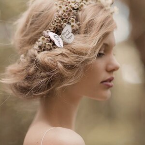 A bride wears a floral crown with a silk butterfly hair pin personalised with a photo of a man and the text "Miss you so much Papa" in her hair.