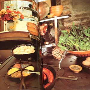 May include: A close-up of a cast iron stovetop with multiple pots and pans. The stovetop is black and has a variety of different foods cooking on it, including potatoes, sausage, and a red sauce.