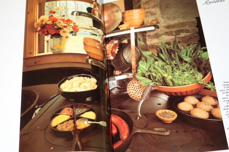 May include: A close-up of a cast iron stovetop with multiple pots and pans. The stovetop is black and has a variety of different foods cooking on it, including potatoes, sausage, and a red sauce.