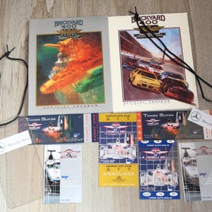 May include: Collection of racing memorabilia, including two "Brickyard 400" official programs and Formula One tickets. The programs feature race car illustrations. Tickets are for Tower Suites and Southeast Vista. A Mercedes-Benz logo is also visible.
