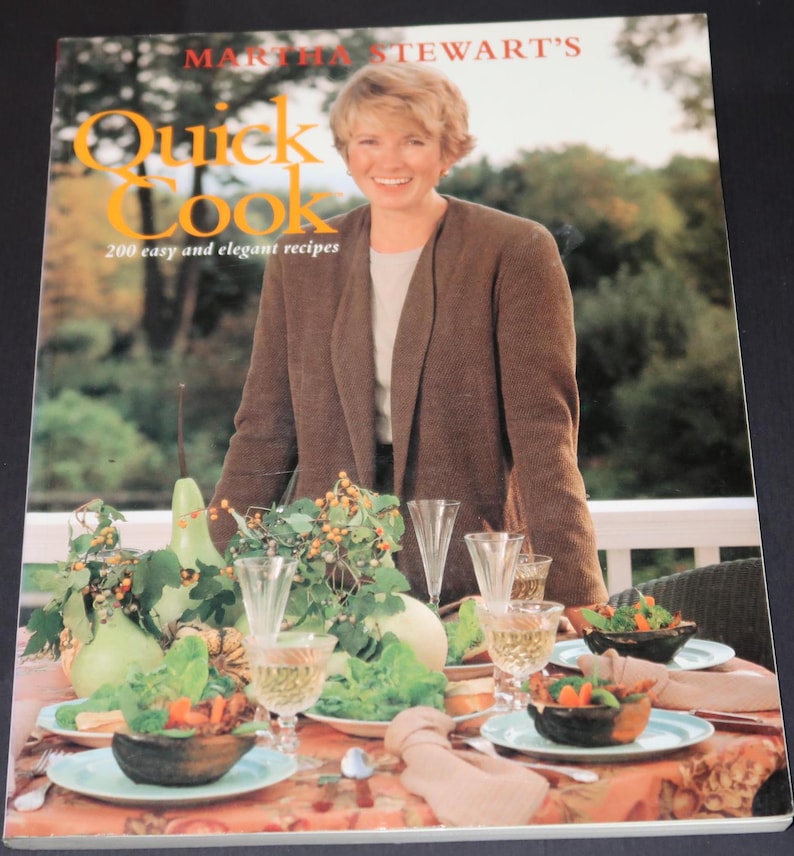 May include: A cookbook titled "Martha Stewart's Quick Cook" with a photo of Martha Stewart on the cover. The book features 200 easy and elegant recipes. The cover also shows a table setting with a floral centerpiece, glasses, and plates.