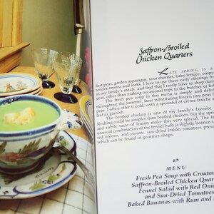 May include: A cookbook page with a recipe for Saffron-Broiled Chicken Quarters. The page includes a photo of a bowl of green pea soup with croutons, a menu listing the recipe, and a description of the dish.