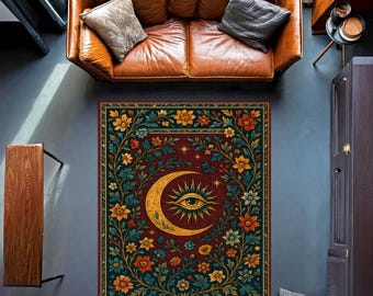 Könnte beinhalten: Rechteckiger Teppich mit einem Himmelsdesign. Der Teppich zeigt einen Halbmond mit einem Auge in der Mitte, umgeben von einem floralen Rand in Gelb-, Orange- und Türkistönen auf burgunderrotem Hintergrund. Der Teppich liegt auf einem grauen Boden.