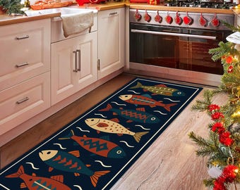 May include: A rectangular kitchen rug with a navy blue background and a repeating pattern of colorful fish. The fish are in shades of red, orange, teal, and yellow, with white wave accents. The rug has a white border and is placed in front of a kitchen cabinet.