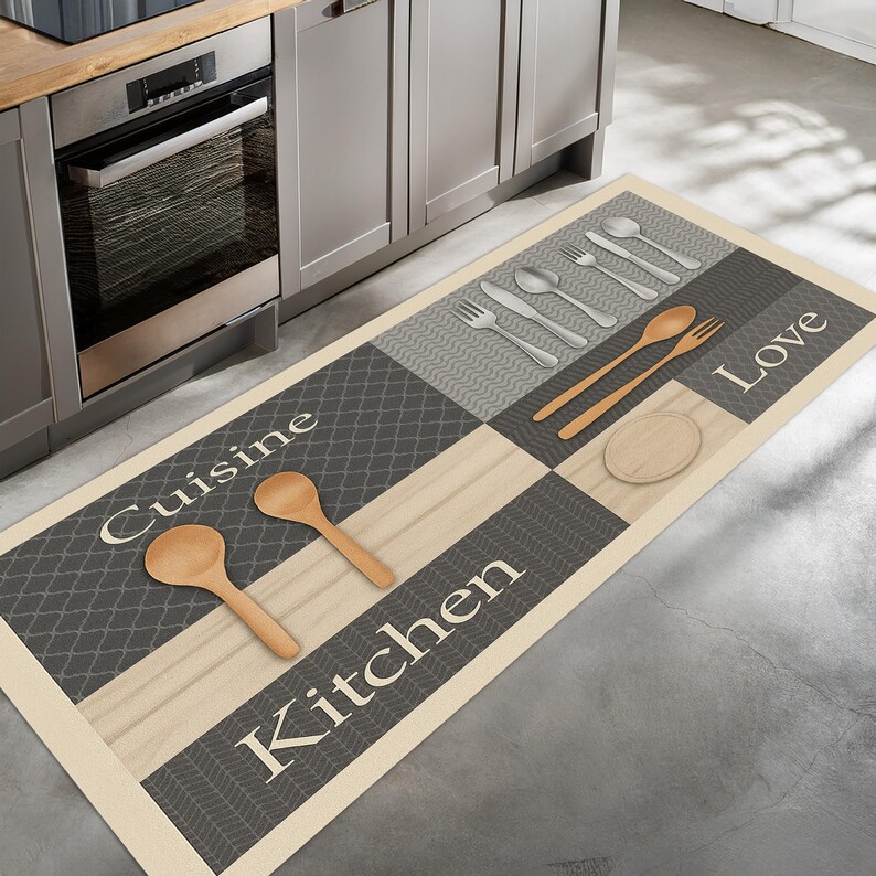 May include: A rectangular kitchen mat with a beige border and a checkered design in gray and light wood tones. The mat features the words "Cuisine Kitchen Love" and illustrations of utensils and wooden spoons.