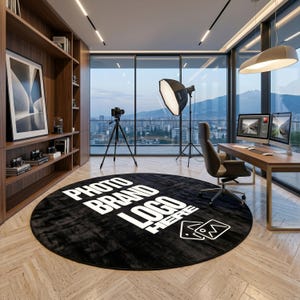 Puede incluir: Una alfombra redonda negra con las palabras "PHOTO BRAND LOGO HERE" en blanco. La alfombra está en un estudio de fotografía con una cámara, luces y un escritorio con dos monitores de computadora. La habitación tiene grandes ventanales con vistas a la ciudad.