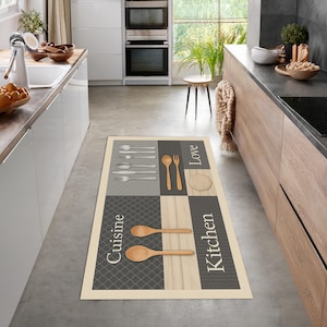 May include: Rectangular kitchen rug with a cream border and a gray, beige, and white patterned design. The rug features images of silverware, wooden spoons, and the words "Cuisine", "Love", and "Kitchen".