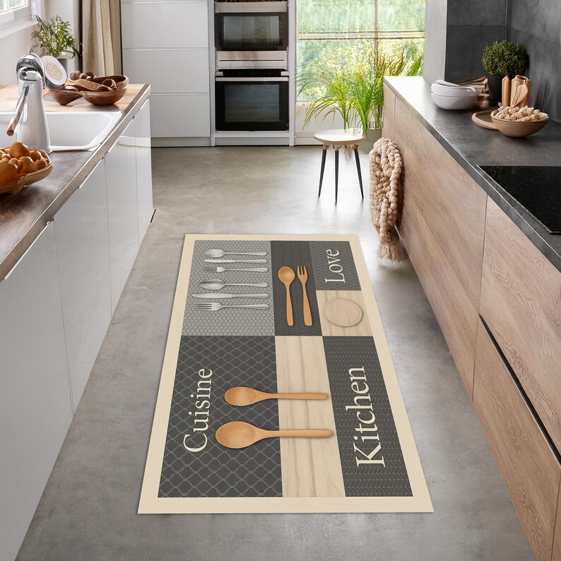 May include: Rectangular kitchen rug with a cream border and a gray, beige, and white patterned design. The rug features images of silverware, wooden spoons, and the words "Cuisine", "Love", and "Kitchen".