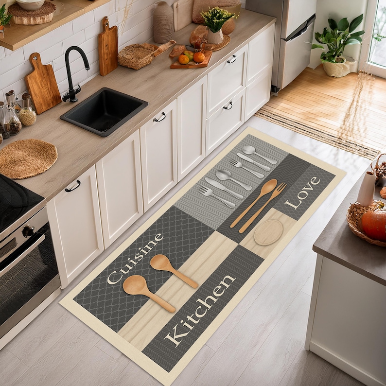May include: A rectangular kitchen floor mat with a cream border and a patchwork design. The mat features gray and beige squares with utensil and text graphics. The words "Cuisine", "Kitchen", and "Love" are printed on the mat.