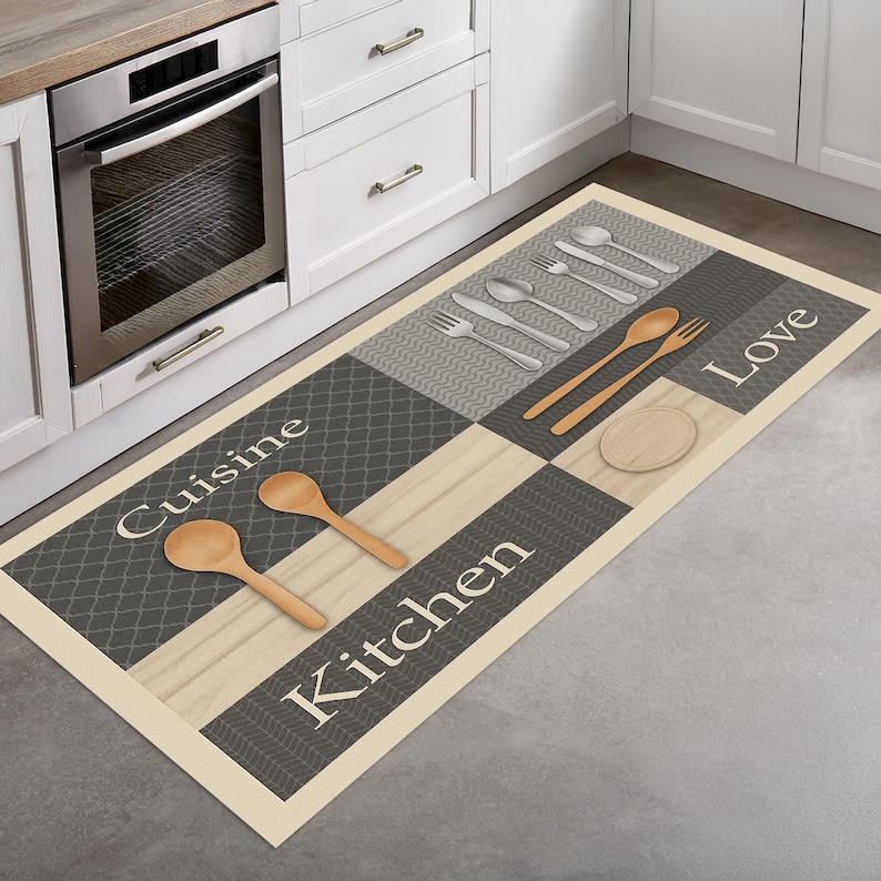 May include: A rectangular kitchen mat with a checkered pattern in gray, beige, and white. The mat features the words "Cuisine Kitchen Love" and images of utensils, including spoons, forks, and a cutting board.