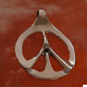 May include: A silver peace sign pendant with a smooth, polished finish. The pendant is shaped like a traditional peace sign with a circular outer ring and a smaller inner circle.
