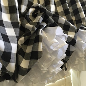 May include: Black and white buffalo check fabric with a white ruffled trim. The fabric is gathered and bunched up, creating a soft and romantic look.