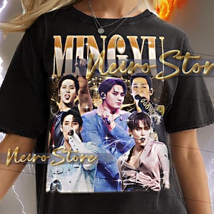Peut inclure: T-shirt noir avec un graphisme d'un groupe de musique, le texte "MINGYU Neiro Stor" en or et le texte "Neiro Store" en or. Le t-shirt est porté par une personne.