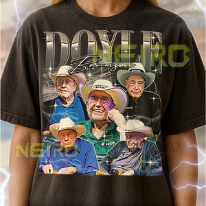 Pode incluir: Camiseta unissex cinza escuro com um gráfico de Doyle Brunson e o texto "DOYERO". O design inclui várias imagens de Doyle Brunson usando chapéus de cowboy. A camisa tem um visual vintage e desgastado.