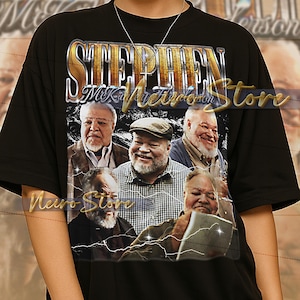 May include: Black unisex t-shirt featuring a graphic of multiple men with the text "STEPHEN MK Metrson Store" in gold lettering. The shirt has a vintage aesthetic with a lightning bolt design.