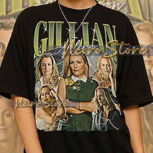 May include: Black unisex t-shirt featuring a graphic of Gillian Anderson with the text "GILLIAN Anderson". The design includes multiple images of the actress. The shirt is a unisex style.