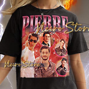 Op de afbeelding: Zwart t-shirt met een retro design met de tekst "PIERRE Meyo Store" en portretten van mannen. Het shirt heeft een vintage esthetiek met een versleten look en een vurige achtergrond.