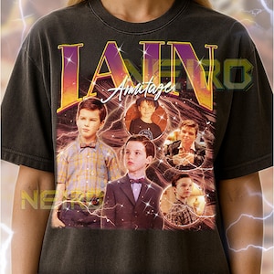 May include: Dark gray unisex t-shirt featuring a graphic of Ian Armitage with the name "IAN" in large, colorful letters. The design includes multiple images of the actor and lightning bolt accents.