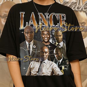 May include: Black t-shirt featuring a graphic of several men in suits and a police uniform. The word "LANCE" is printed across the top in gold lettering. The shirt is a unisex style.