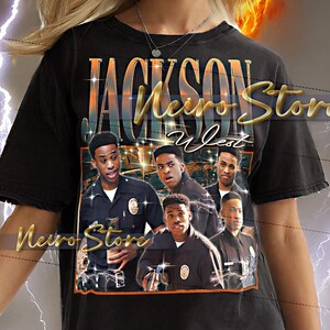 May include: Black t-shirt with a graphic featuring the text "JACKSON Neuro Store West" and a photo of five men. The shirt is worn by a person with blonde hair and earrings. The background has a yellow and orange design.