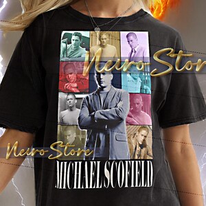 Op de afbeelding: Zwart T-shirt met een collage van afbeeldingen en de naam "MICHAEL SCOFIELD" in het wit. Het shirt heeft een versleten uitstraling en wordt door een persoon gedragen. De tekst "Neiro Store" is ook zichtbaar.