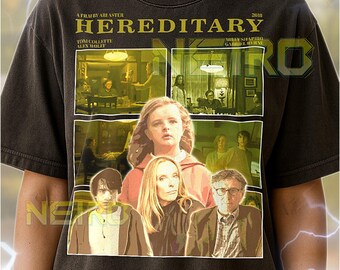 May include: Dark gray unisex t-shirt featuring a movie poster design for "Hereditary." The graphic includes the film's title, cast, and a collage of scenes. The shirt has a crew neck and short sleeves.