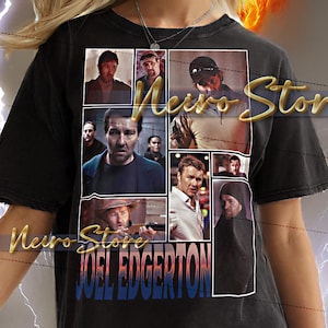 May include: Black unisex t-shirt featuring a collage of images and the name "JOEL EDGERTON" in blue and white. The shirt has the text "Meirs Stor" in a gold script. The model is wearing a 2XL shirt.
