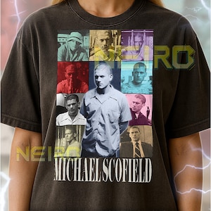 Op de afbeelding: Donkergrijs unisex T-shirt met een collage van afbeeldingen van Michael Scofield met de naam "MICHAEL SCOFIELD" in witte blokletters. Het shirt heeft een ronde hals en korte mouwen. De tekst op het shirt luidt: Het eerste model draagt een XL shirt. Dit unisex shirt valt normaal. Voor een oversized look, selecteer 1 of 2 maten groter dan je gebruikelijke maat. Je kunt de maattabel raadplegen.