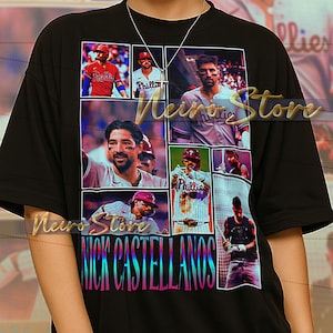 May include: Black unisex t-shirt featuring a collage of baseball player images and the name "NICK CASTELLANOS" in a colorful, gradient font. The shirt has a crew neck and short sleeves. The text at the bottom of the image is not included.