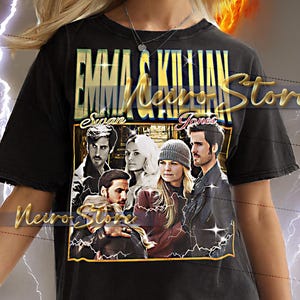 Könnte beinhalten: Schwarzes T-Shirt mit einer Grafik von Charakteren und dem Text "Emma & Killian Jones Swan Neiro Store". Das Shirt hat einen Rundhalsausschnitt und kurze Ärmel. Das Model trägt eine weiße Hose.