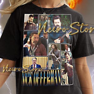 May include: Black unisex t-shirt with a collage of images and the name "Nick Offerman" in gold lettering. The shirt has a distressed look and is worn by a person. The shirt is a 2XL size.