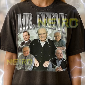 May include: Dark gray unisex t-shirt featuring a graphic of Mr. Feeny with the text "MR. FEENY" in a metallic silver font. The shirt includes a photo collage of Mr. Feeny. The shirt fits true to size.