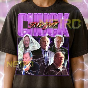 May include: Dark grey unisex t-shirt with a purple graphic reading "CHUCK McGill" and images of men. The shirt also features the text "NEL" and a size guide.