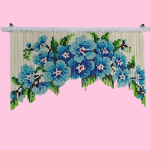 May include: A beaded curtain with a floral design featuring blue, green and white beads. The curtain is hung from a white rod.