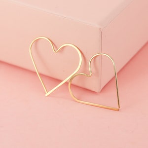 May include: A pair of gold heart-shaped hoop earrings. The earrings are simple and elegant, and would make a great gift for any occasion.