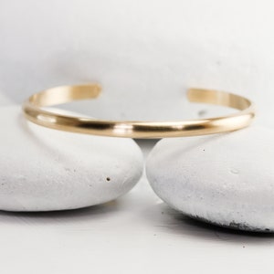 Personalized Custom Stamped Wide Gold Cuff with Brushed/Matte Finish by Lotus Stone Jewelry on white stones