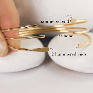 Smooth, polished, gold cuff with flared hammered ends for accentuation on white stones showing options to get 0, 1, or both ends hammered.