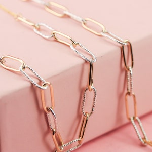 May include: A gold and silver chain necklace with oval links. The chain is made of two different metals, with one side being gold and the other side being silver.