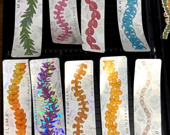 May include: A collection of holographic stickers featuring floral designs and the text "NA LIMA MADE." The stickers showcase various flower and leaf patterns in colors like green, pink, orange, and blue. Each sticker has a unique name.
