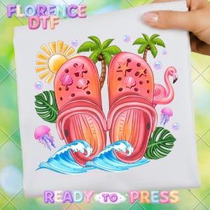 May include: A white graphic featuring a pair of pink clogs decorated with seashells and starfish, palm trees, a flamingo, and ocean waves. The image includes the text "FLORENCE DTF" and "READY TO PRESS".