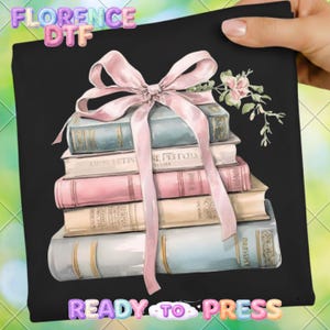 May include: Black graphic featuring a stack of vintage books in pastel colors, tied with a pink ribbon and adorned with a floral sprig. The text "FLORENCE DTF" and "READY TO PRESS" are visible.