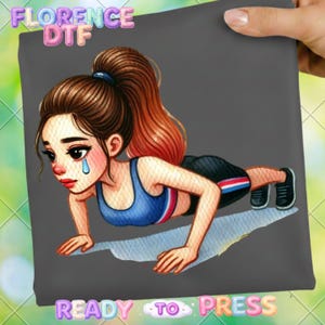 May include: A gray graphic featuring a cartoon woman doing push-ups, with a tear falling from her eye. She wears a blue sports bra and black shorts with red and white stripes. The text "FLORENCE DTF" and "READY TO PRESS" are visible.