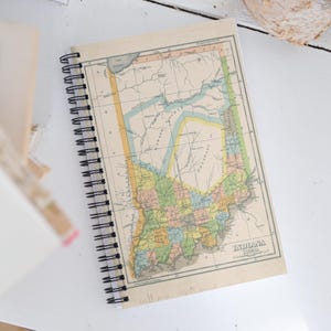 May include: A vintage spiral bound notebook with a map of Indiana from 1872 on the cover. The map is in shades of blue, green, yellow, and pink. The notebook is perfect for journaling, taking notes, or sketching.