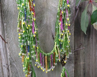 Thousands of periwinkle blue, blush, pink, raspberry, tangerine, purple, peach, lemon yellow glass beaded fringe cascading from peridot....