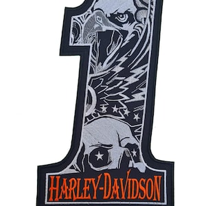 Op de afbeelding: Zwarte en witte geborduurde patch met een Harley-Davidson logo en een nummer één. Het nummer één is gevuld met een adelaar, schedel en sterren.