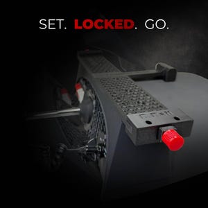 May include: Black device with a textured surface and a red knob. The device has the text "SET. LOCKED. GO." in white and red. The device appears to be a component of a larger system.
